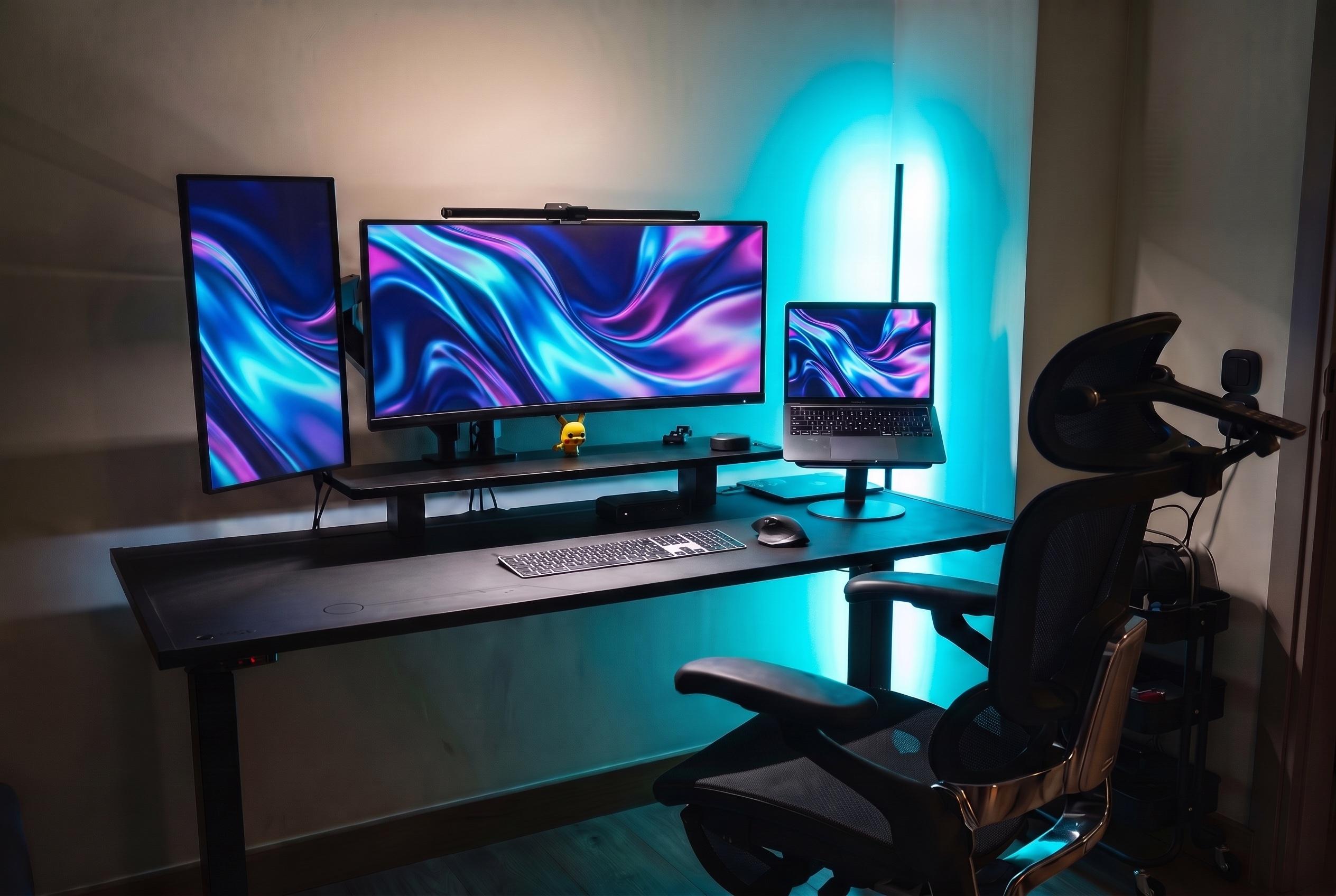 The same workspace at night from the chair side, abstract wallpaper on the screens