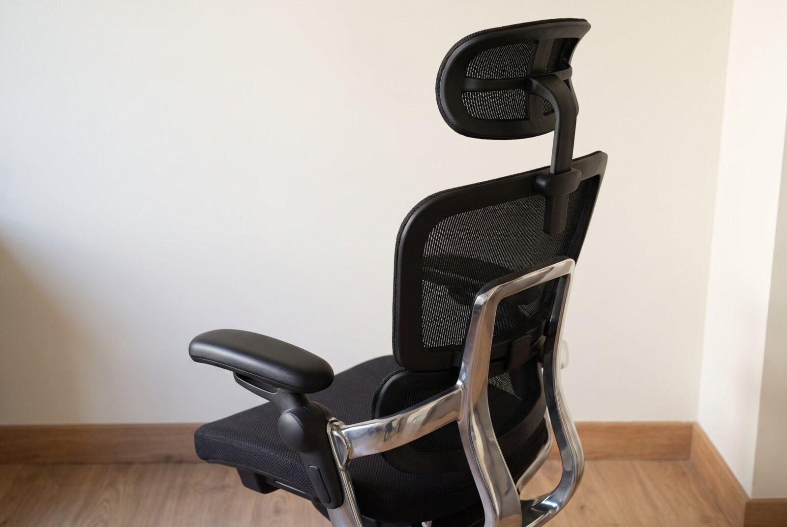 Detail of the assembled chair: the adjustable headrest on its stem, the mesh backrest and one padded armrest